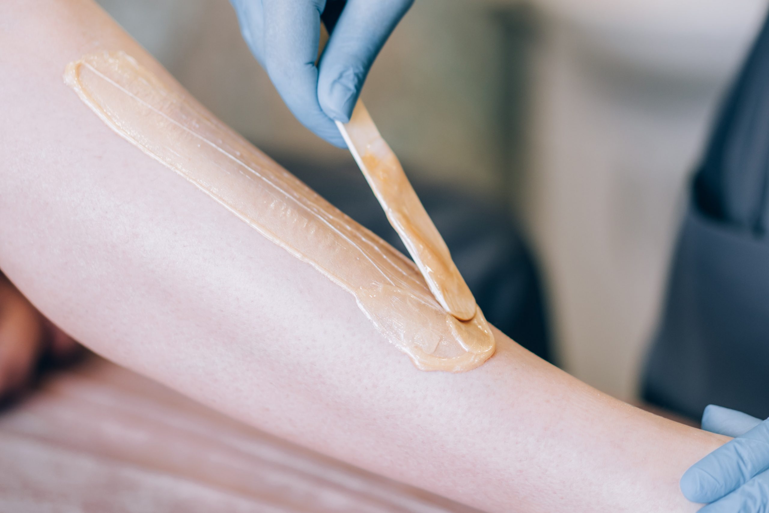 The specialist depilates the hair with wax on the leg